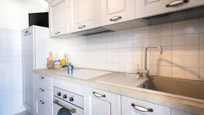 Eine moderne Küche mit weißen Schränken, einer Edelstahlspüle und einem eingebauten Backofen.