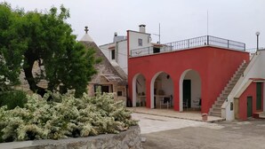 Ein Innenhof mit einem roten Gebäude, einer Steinmauer und weißen blühenden Pflanzen.