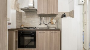 A compact kitchen with a gas stove, oven, and white refrigerator. - GuestHost - Casa Vita 49 in Ceglie Messapica (Ceglie Messapica)
