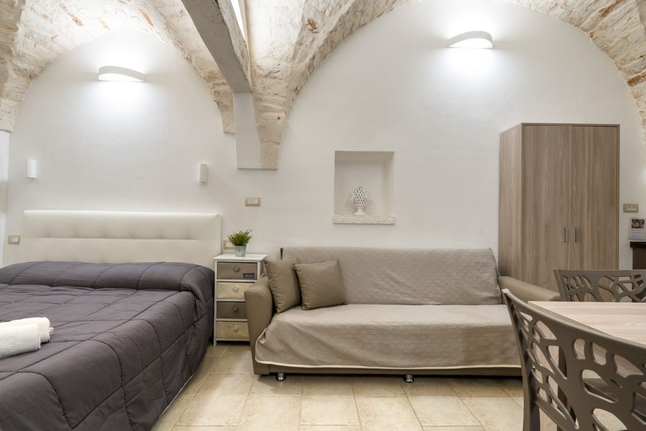 Un dormitorio con cama, sofá, mesita de noche, armario y comedor.