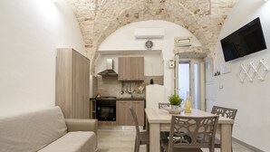 A modern kitchen with an arched stone ceiling, a dining area with a table and chairs, and a TV mounted on the wall. - GuestHost - Casa Vita 49 in Ceglie Messapica (Ceglie Messapica)