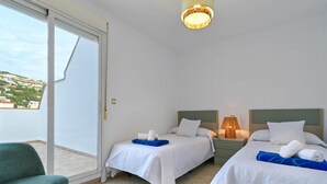 A hotel room with two beds, a green chair, and a sliding glass door leading to a balcony. - Wonderful and classic apartment in Javea, Costa Blanca, Spain for 4 persons (Javea)