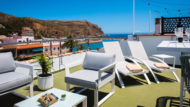 A rooftop terrace with white lounge chairs, a small table, and a potted plant. - Wonderful and classic apartment in Javea, Costa Blanca, Spain for 4 persons (Javea)