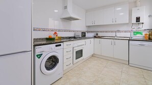A modern kitchen with white cabinets, a built-in washing machine, a microwave, and a dishwasher. - Wonderful and classic apartment in Javea, Costa Blanca, Spain for 4 persons (Javea)