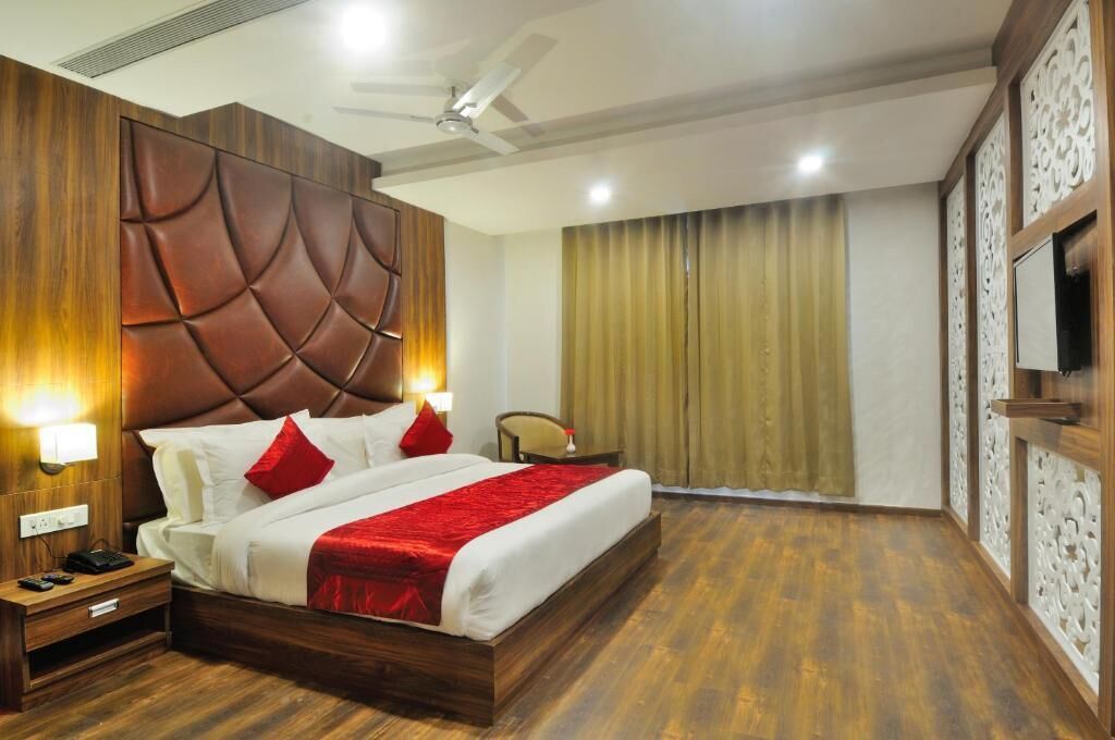 Ein Hotelzimmer mit einem großen Bett, einem Holz-Kopfteil, zwei Nachttischlampen, einem Deckenventilator und einem an der Wand befestigten Fernseher.