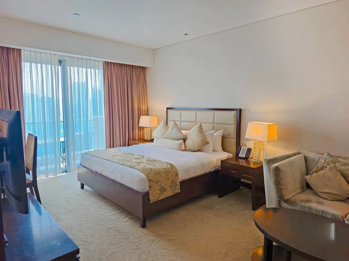 A hotel room with a large bed, a sofa, a desk, and a chair.