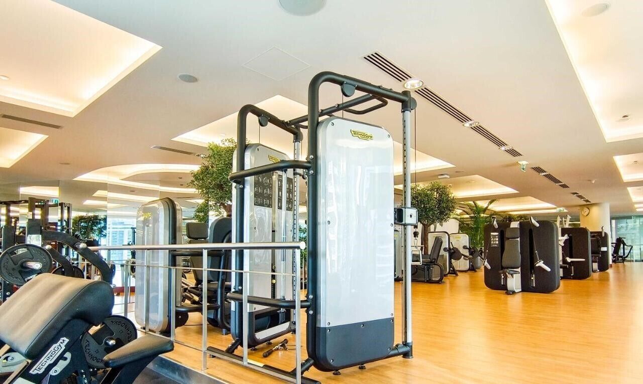 A gym with various exercise equipment, including a Smith machine and weight benches.