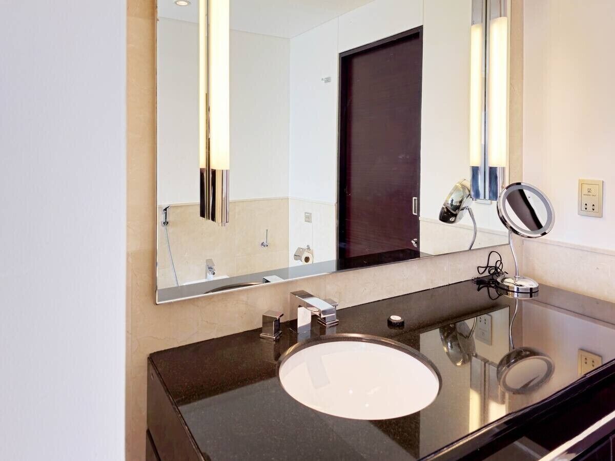 A modern bathroom with a large mirror, a round sink, and a dark countertop.