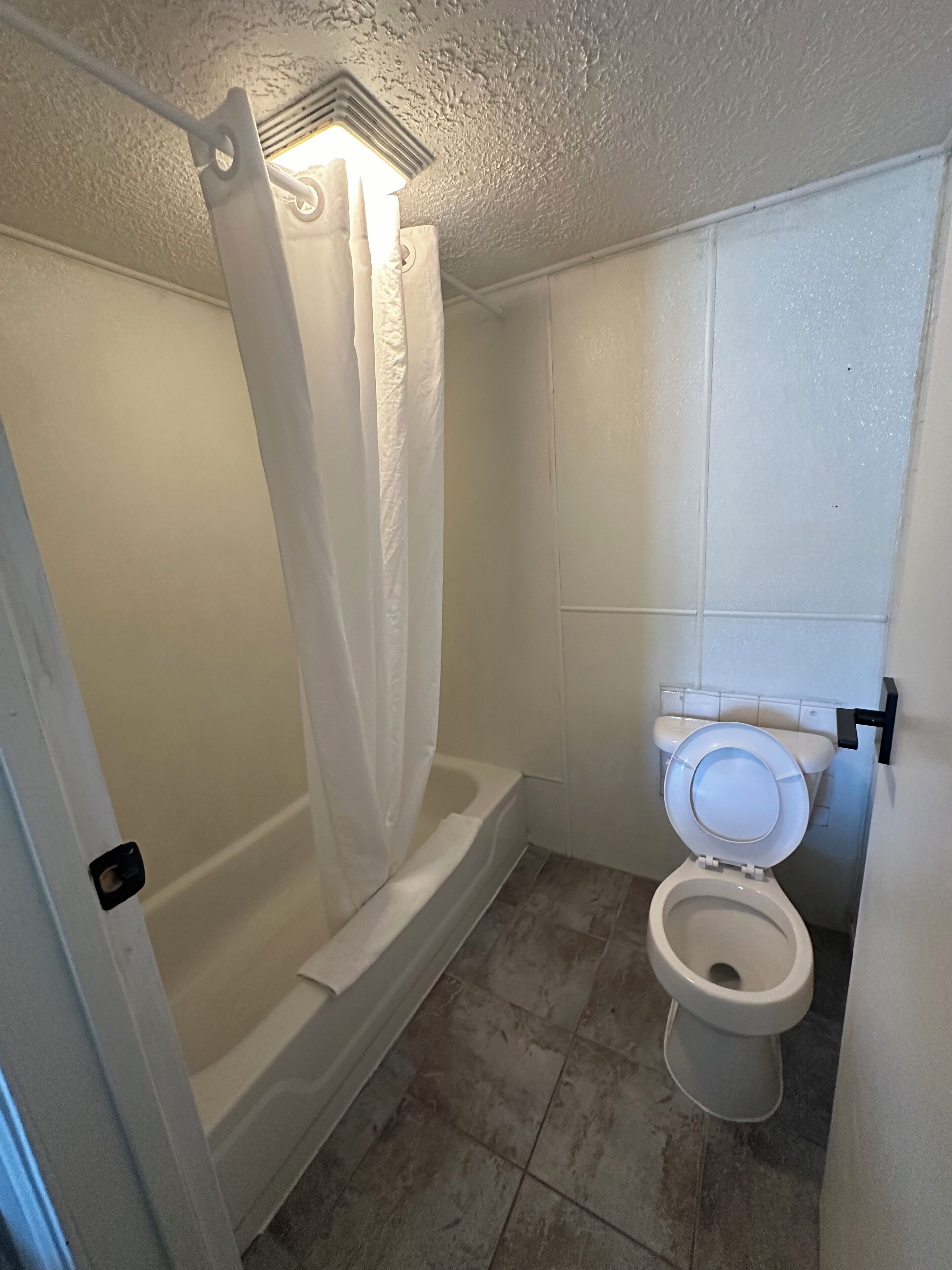 A bathroom with a bathtub, toilet, and shower curtain.