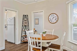 A dining area with a round table, white chairs, and a wall clock. - Marvelous Single Level Home in Central Newberg, Fire-Table, Covered Patio, Seven Blocks to Downtown (Newberg)