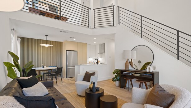 Un vaste espace de vie comprenant un canapé, des fauteuils et une table basse. Un escalier doté d’une rampe mène à l’étage supérieur.