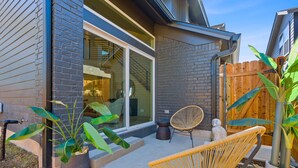 Une maison moderne dotée d’une grande porte vitrée, d’une terrasse en bois et d’un espace salon extérieur.