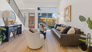 Un salon spacieux doté d’un escalier moderne, d’une grande fenêtre offrant une belle vue et d’un coin salon confortable.