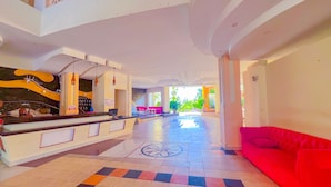 Eine großzügige Lobby mit einer Rezeption, einem roten Sofa und einem gemusterten Boden.