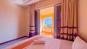 Ein Hotelzimmer mit Bett, Blick auf einen Balkon und einer zur Außenseite führenden Tür.