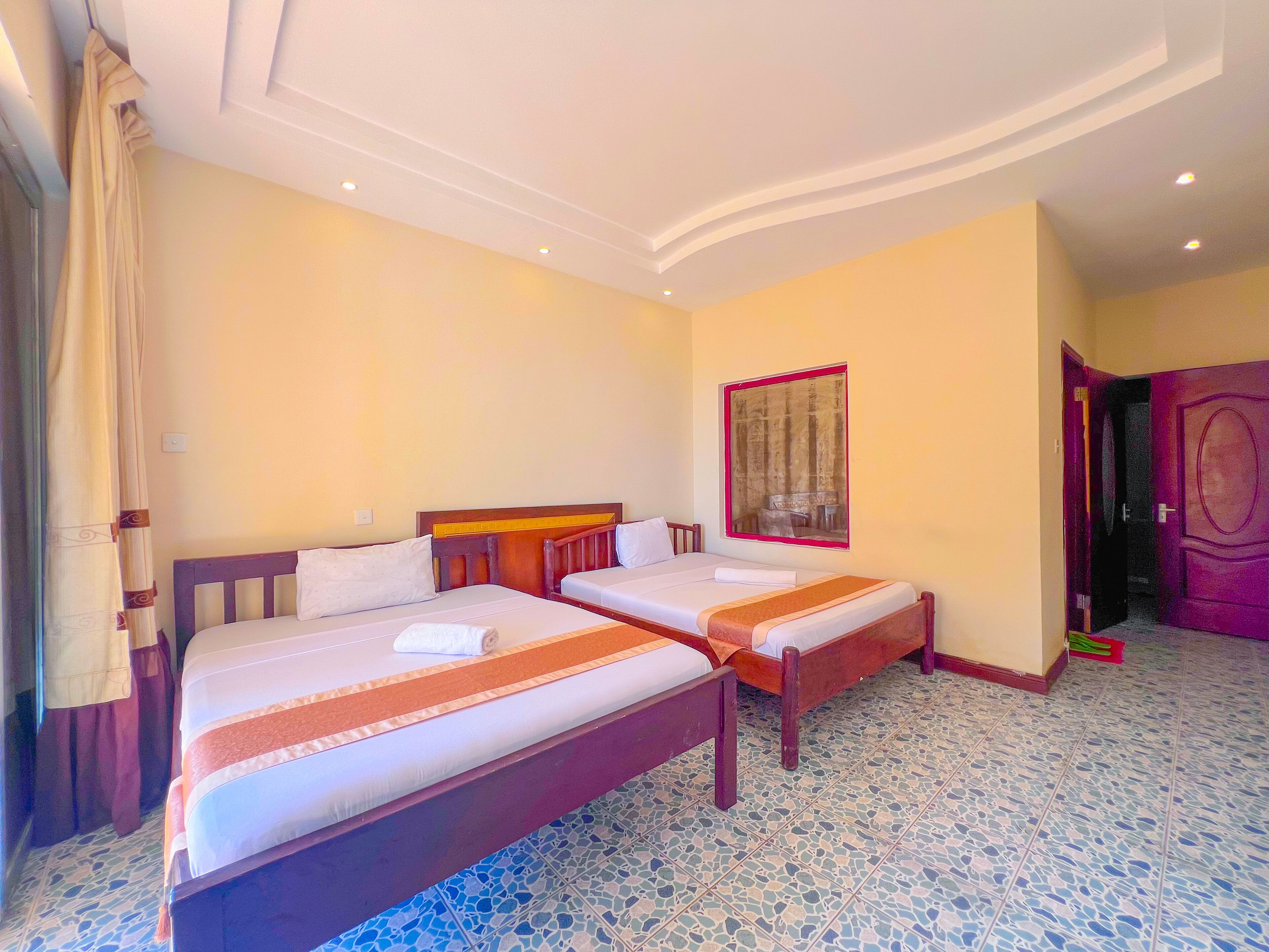 Una habitación de hotel con dos camas, un ventanal con vistas y suelo de baldosas.