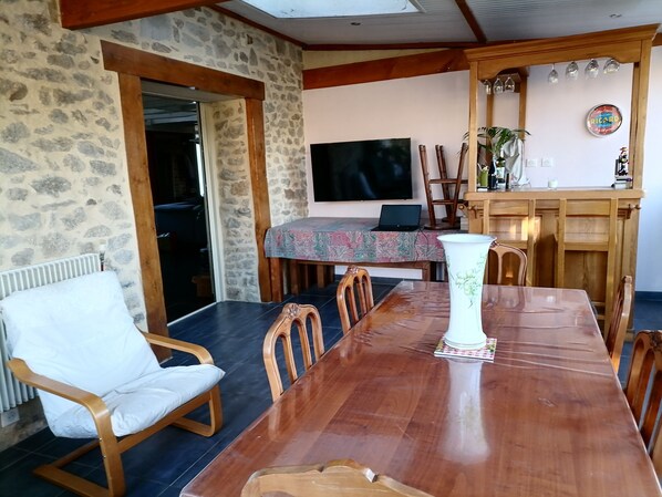 A dining area with a wooden table, chairs, a vase, and a television.