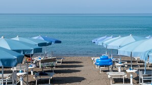 A beach with rows of blue umbrellas and white lounge chairs. - Residence Stella Marina (Cecina)