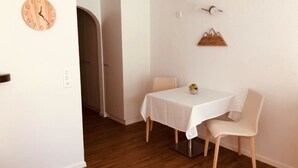 Un comedor con una mesa y sillas, un reloj de madera y una lámpara fijada a la pared.
