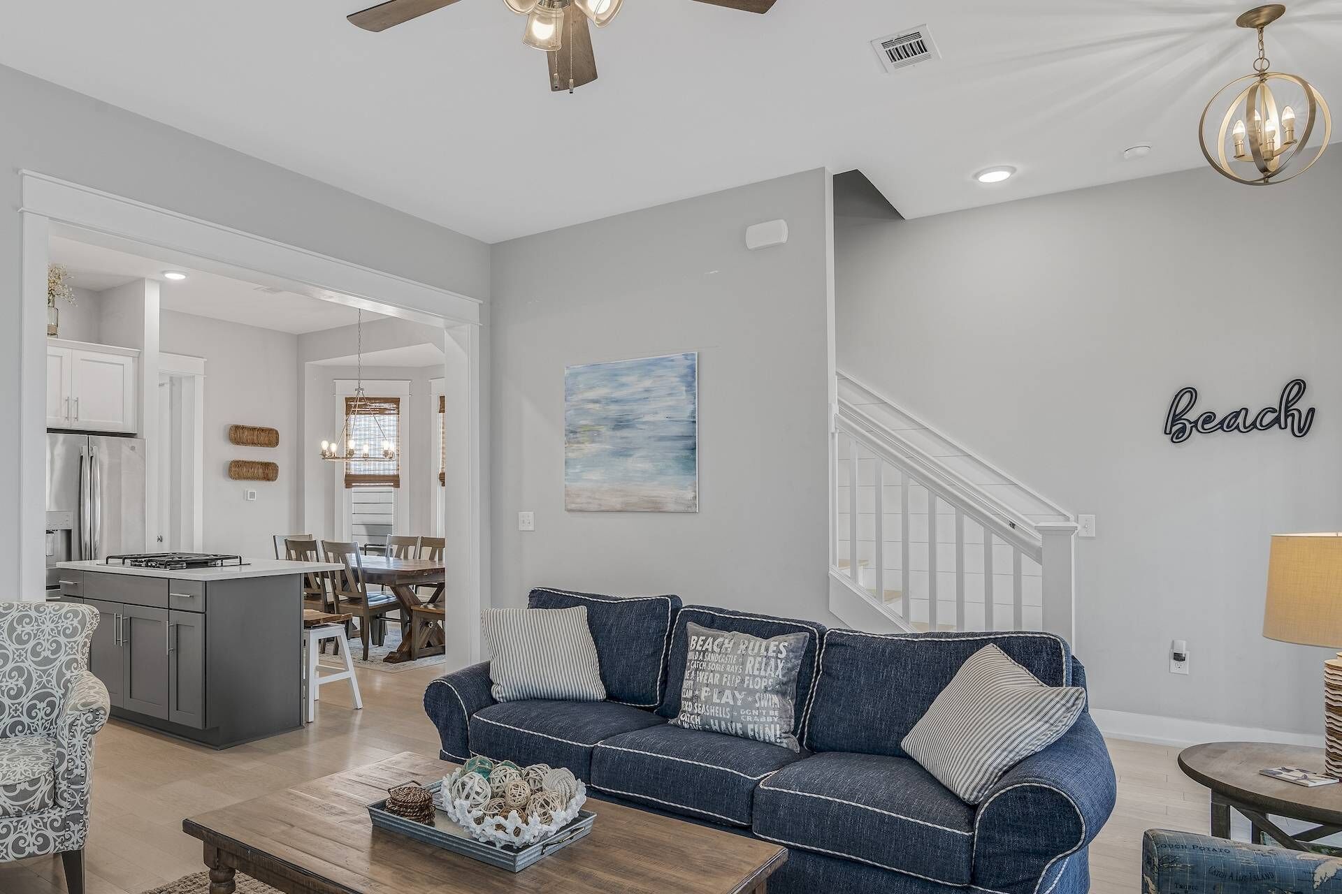 A modern living room with a blue sofa, wooden coffee table, and a chandelier.