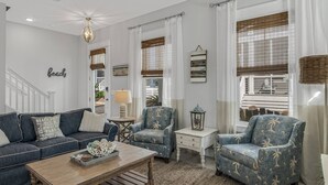 Un salon comprenant un canapé, deux fauteuils, une table basse et une lampe. Un escalier mène à un niveau supérieur.