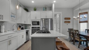 Une cuisine moderne avec des meubles blancs, des appareils en acier inoxydable et un îlot central.