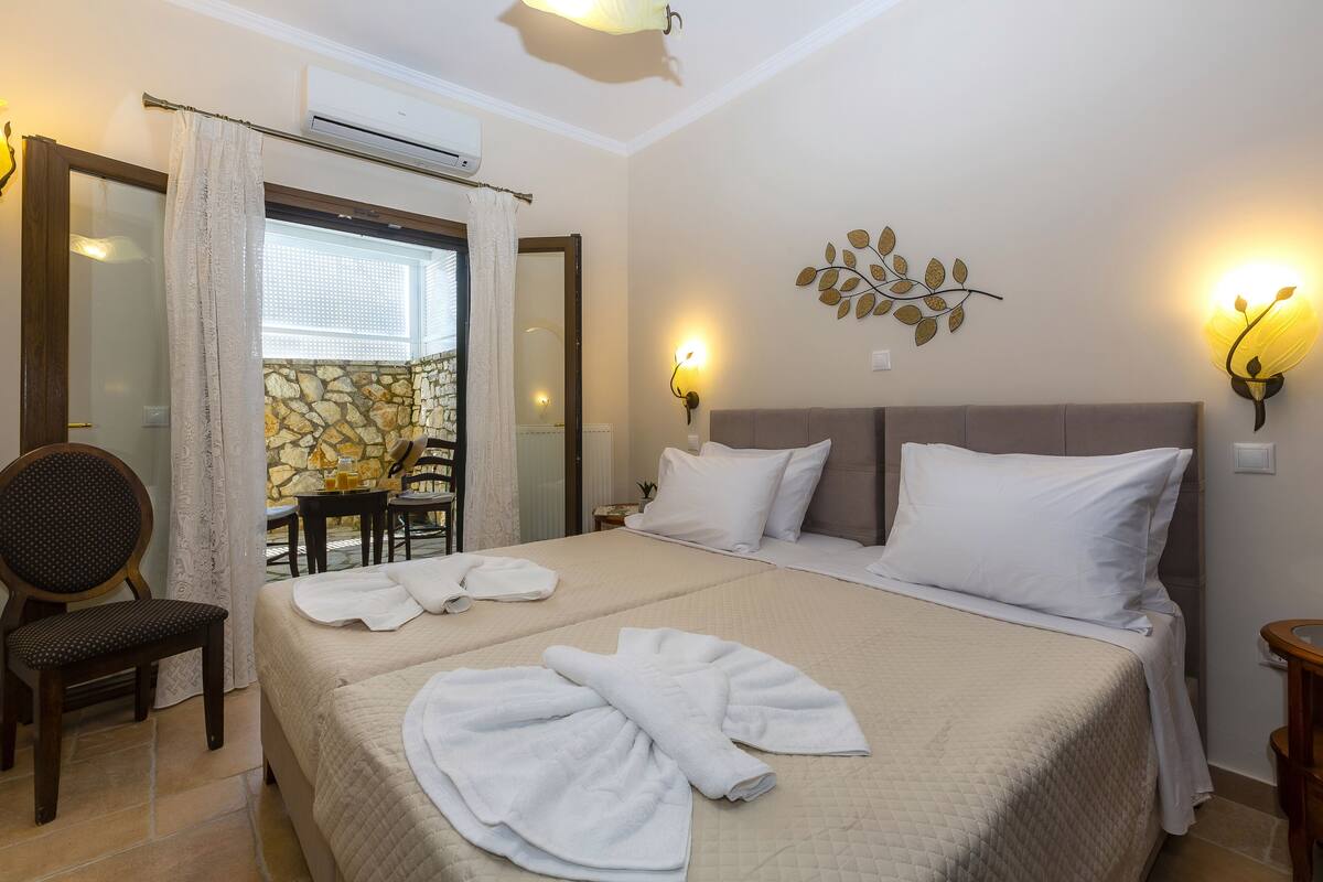 A hotel room with a large bed, two bedside tables, a chair, and a stone wall.
