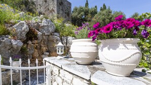 A stone wall with a white fence, large white pots with flowers, and a lantern. - Solaris Methea Deluxe Suites  (Kassiopi)