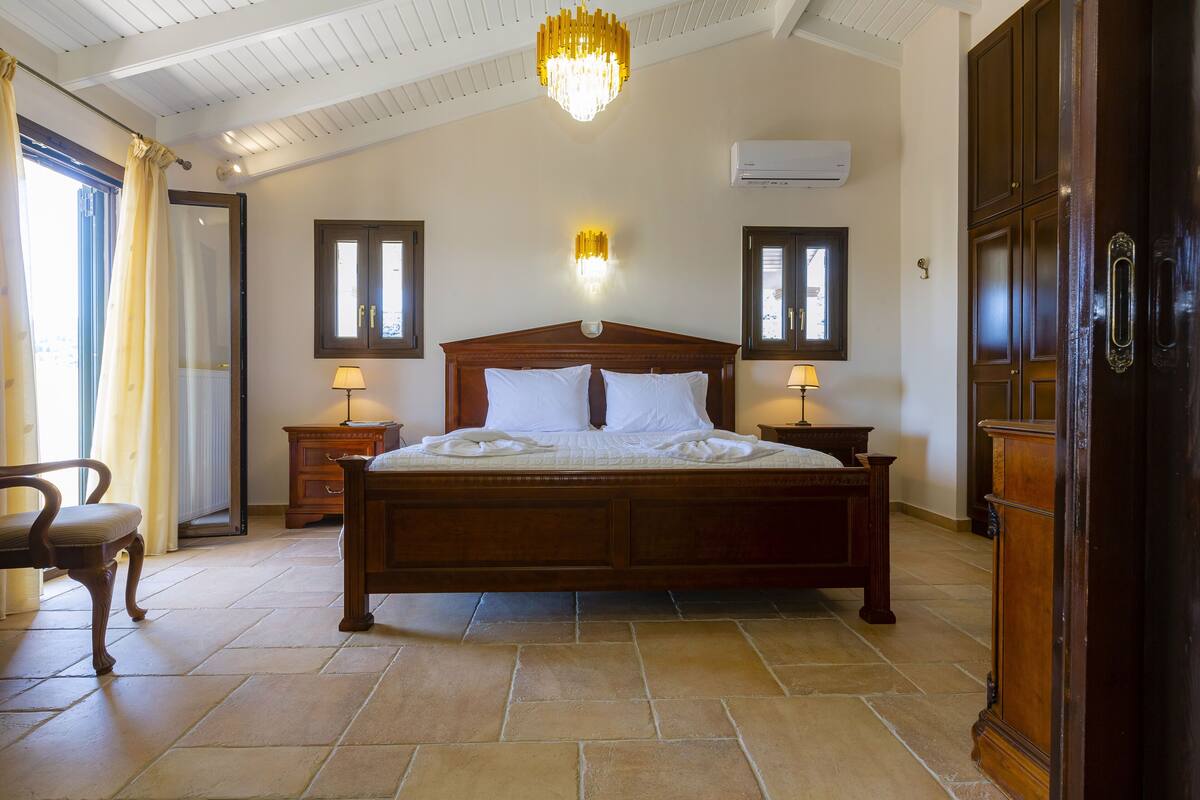 A bedroom with a large bed, two bedside tables, a chandelier, and a wooden wardrobe.