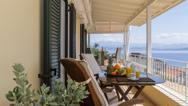 A balcony with a table set for breakfast, a chair, and a view of the sea. - Solaris Methea Deluxe Suites  (Kassiopi)