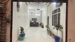 A hallway with a reception desk, potted plants, and a ceiling fan.