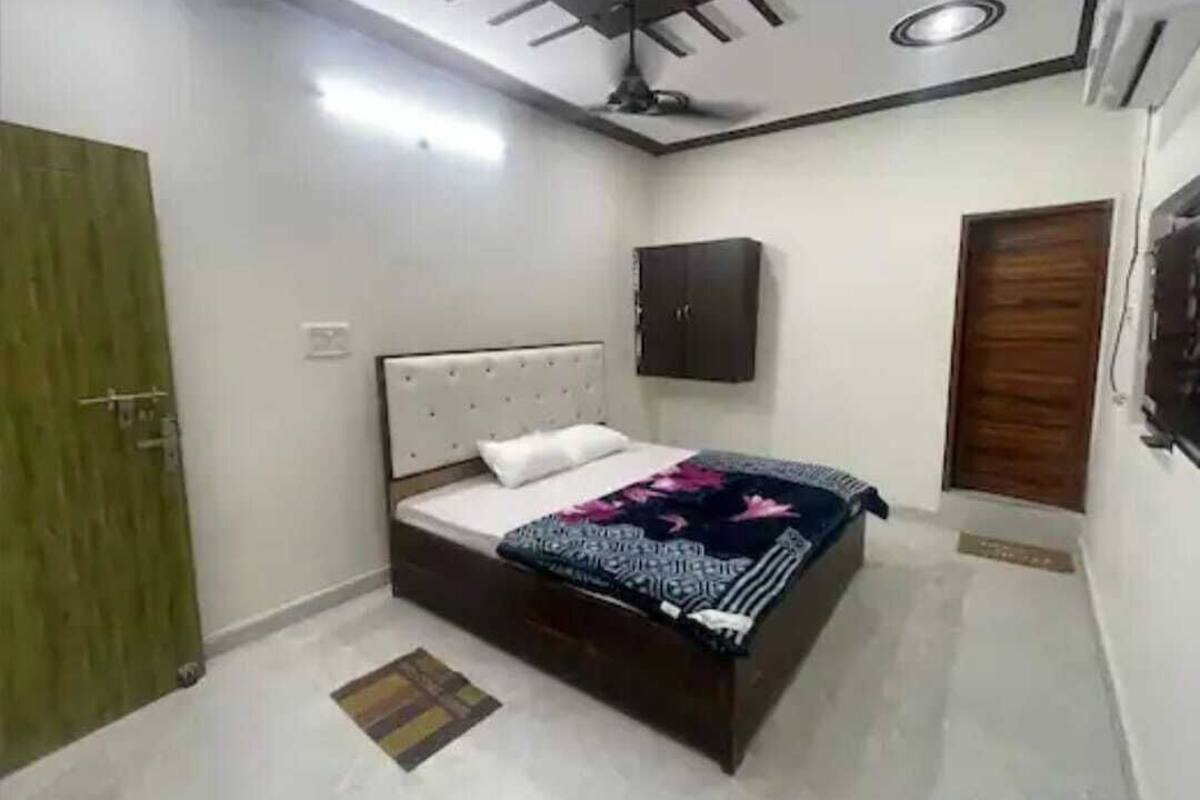 A bedroom with a bed, a wardrobe, a ceiling fan, and a door.