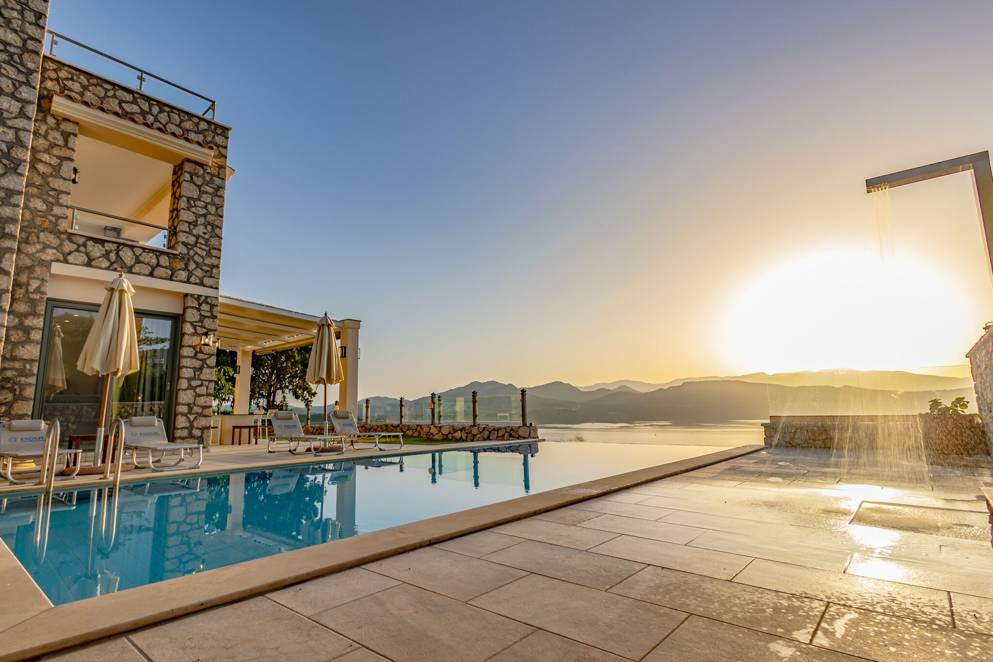 A pool area with lounge chairs and a stone building.