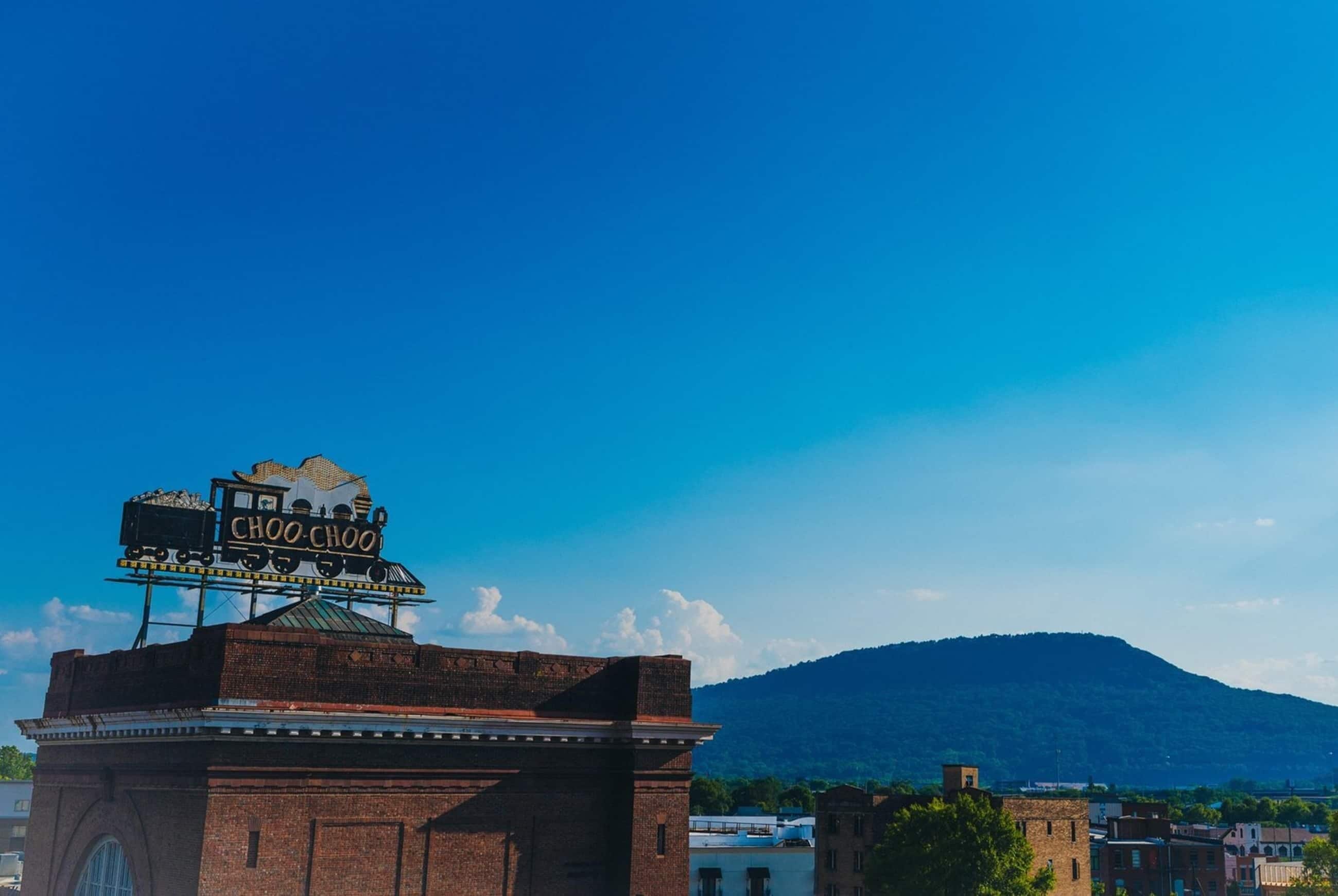 Un bâtiment orné d’une enseigne indiquant « CHOO CHOO », avec une façade en briques et une montagne en arrière-plan.