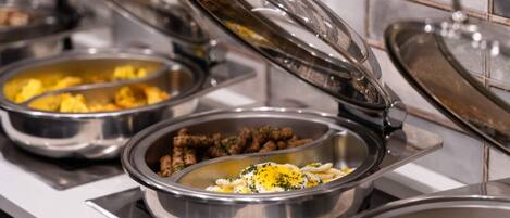 A buffet with various food items in metal bowls, some with lids.