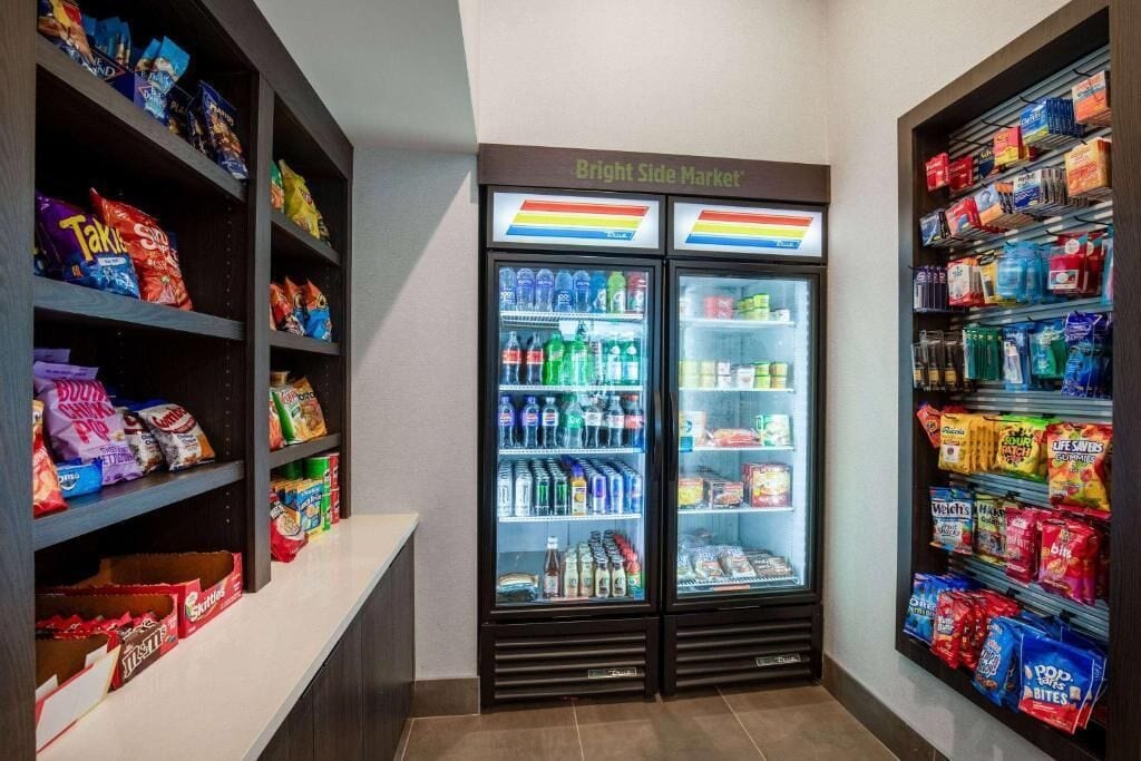 Un espace de vente de collations et de boissons, équipé de deux réfrigérateurs portant l’inscription « Bright Side Market », et proposant une variété de collations et de boissons.