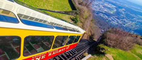 Un chemin de fer de montagne avec un train jaune et rouge, des voies ferrées et une vue sur une vallée.