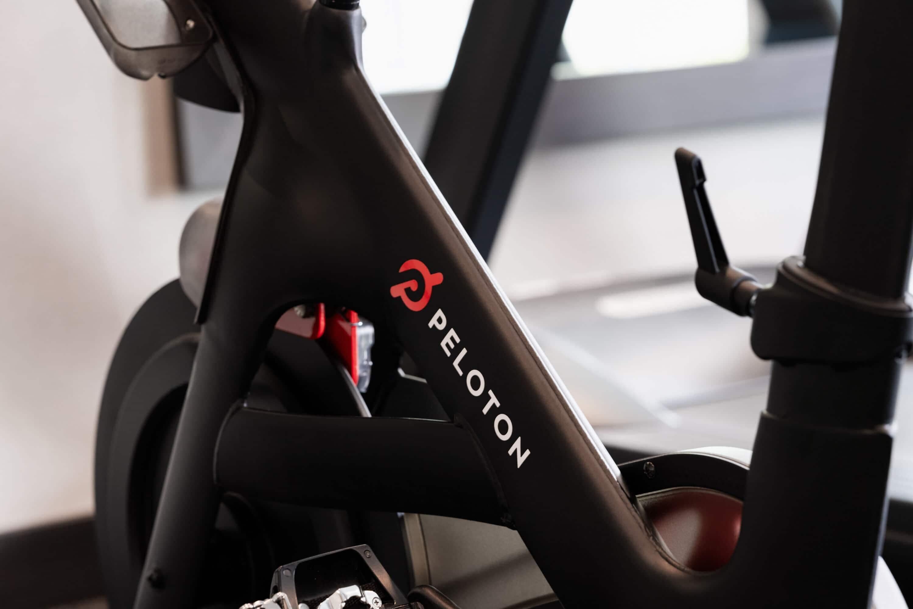 A Peloton stationary bike with a control panel and a red resistance band.
