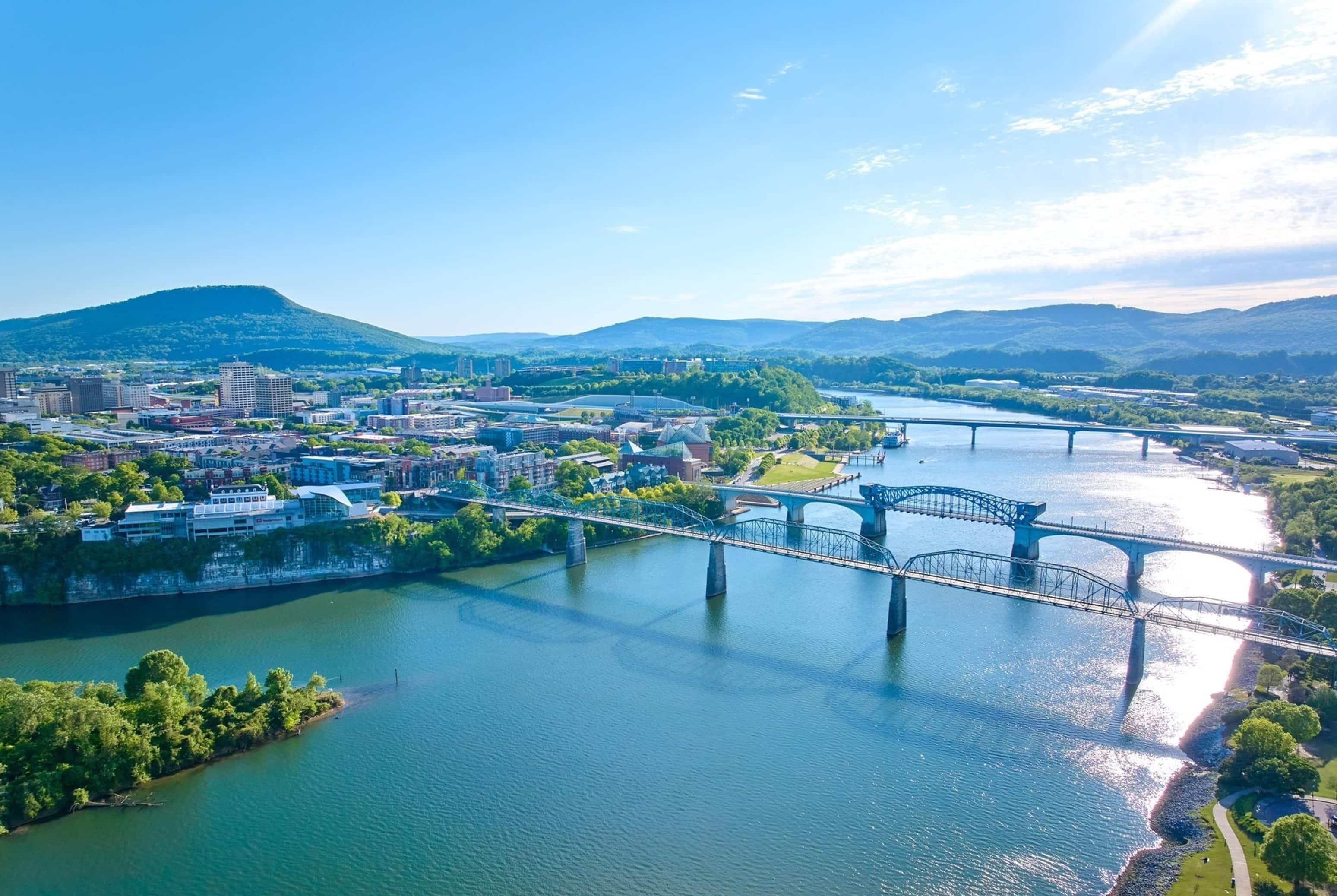 A river with bridges, a cityscape, and hills in the background.