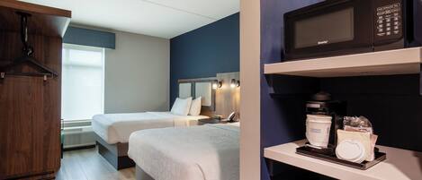 A hotel room with two beds, a wooden wardrobe, a microwave, and a coffee maker on the counter.