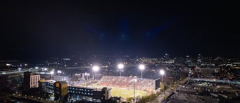 Un estadio con una amplia zona de asientos e iluminación artificial, rodeado de edificios y carreteras.