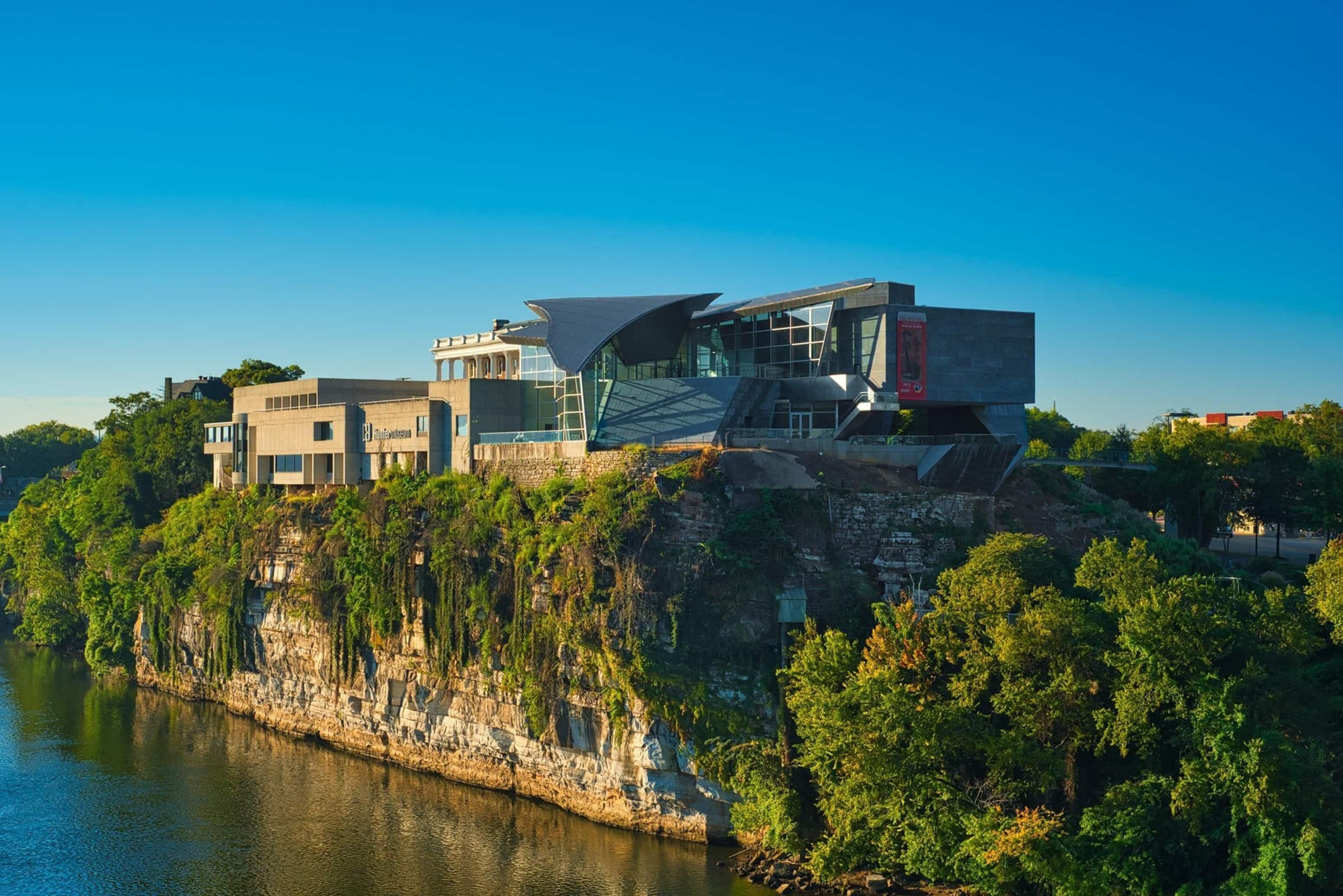 A modern building with a unique architectural design, situated on a cliff overlooking a body of water.