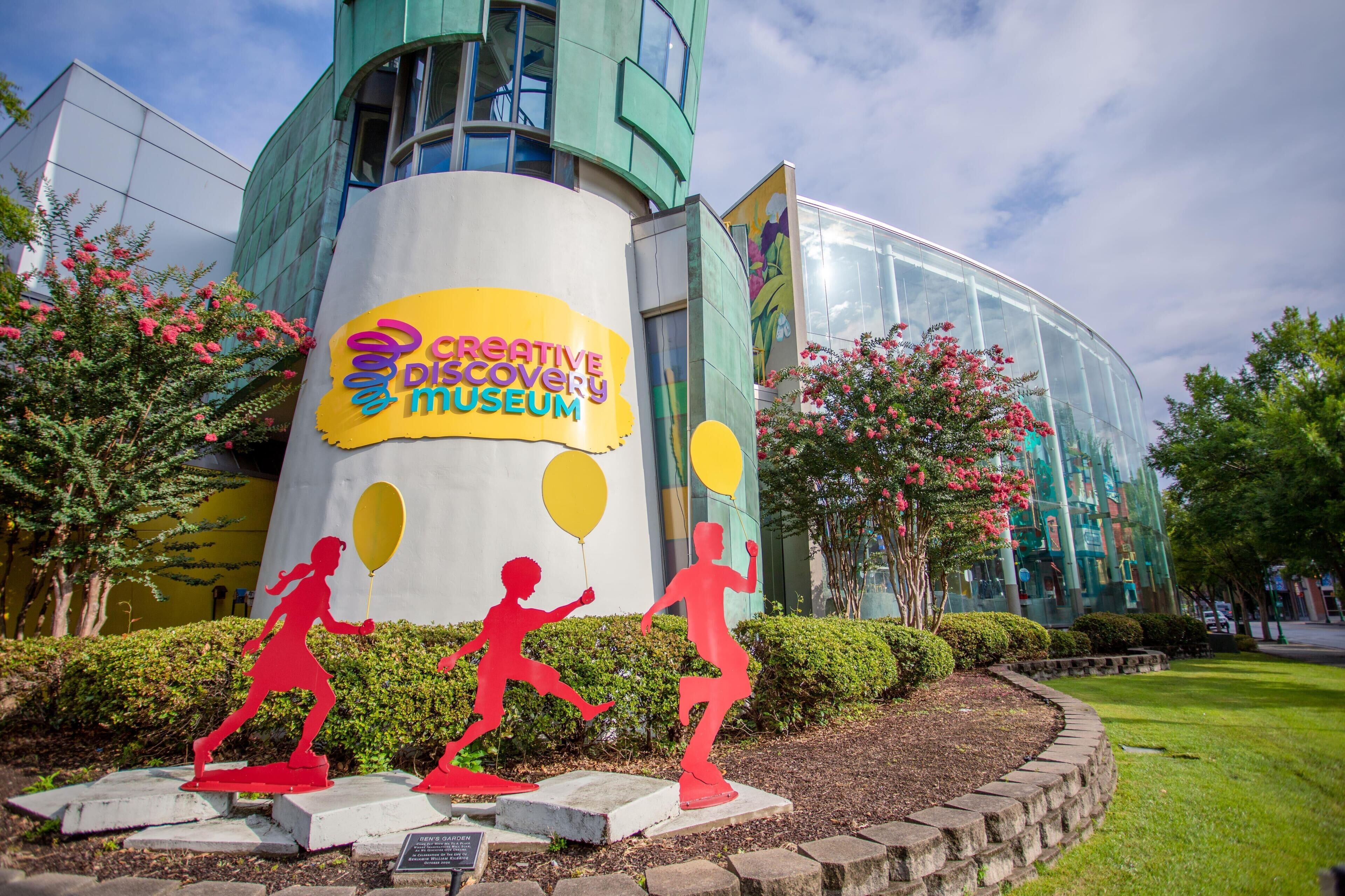 A building with a 'Creative Discovery Museum' sign and three red human figures.