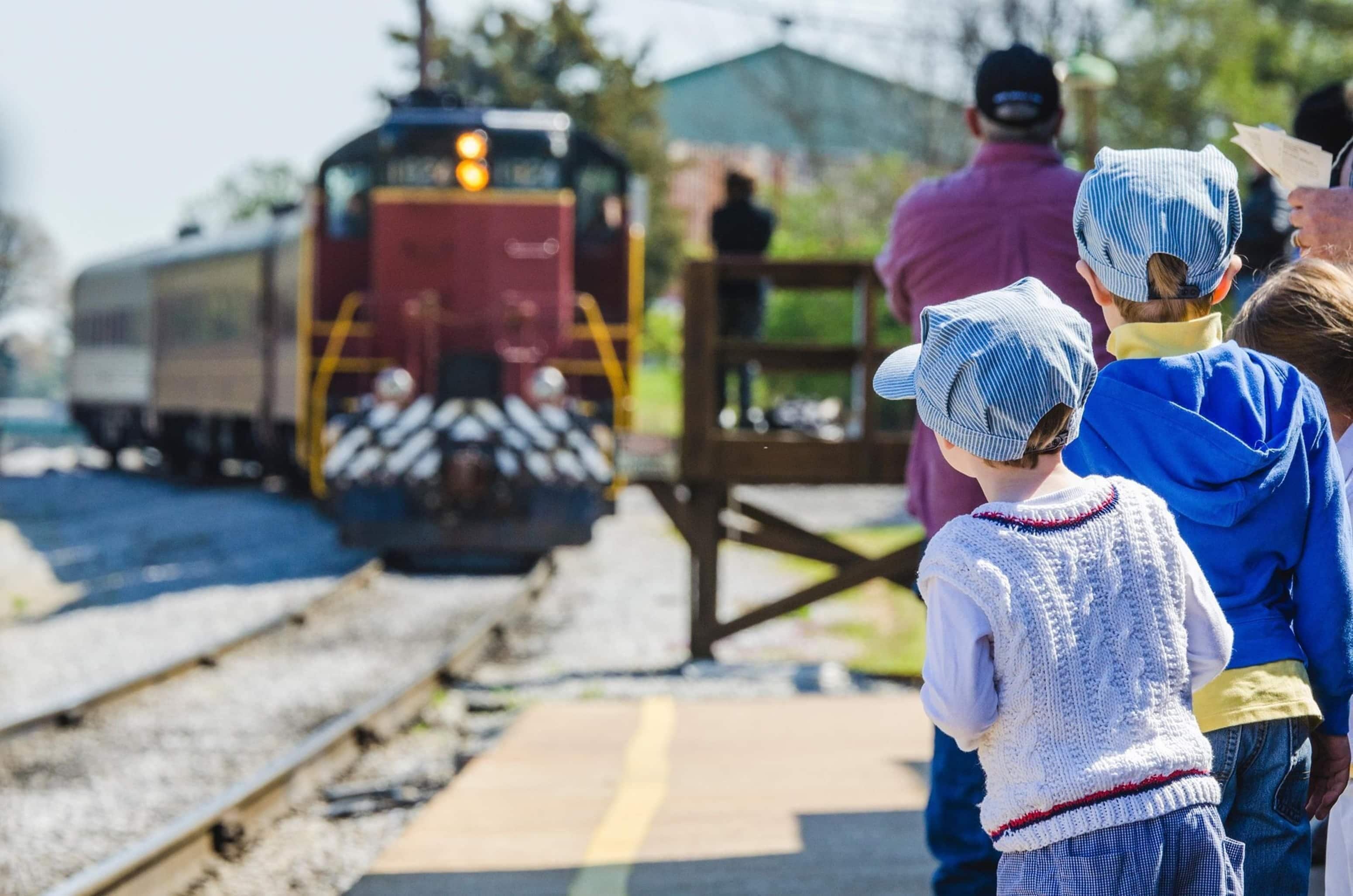 A train on tracks with people standing on the platform.