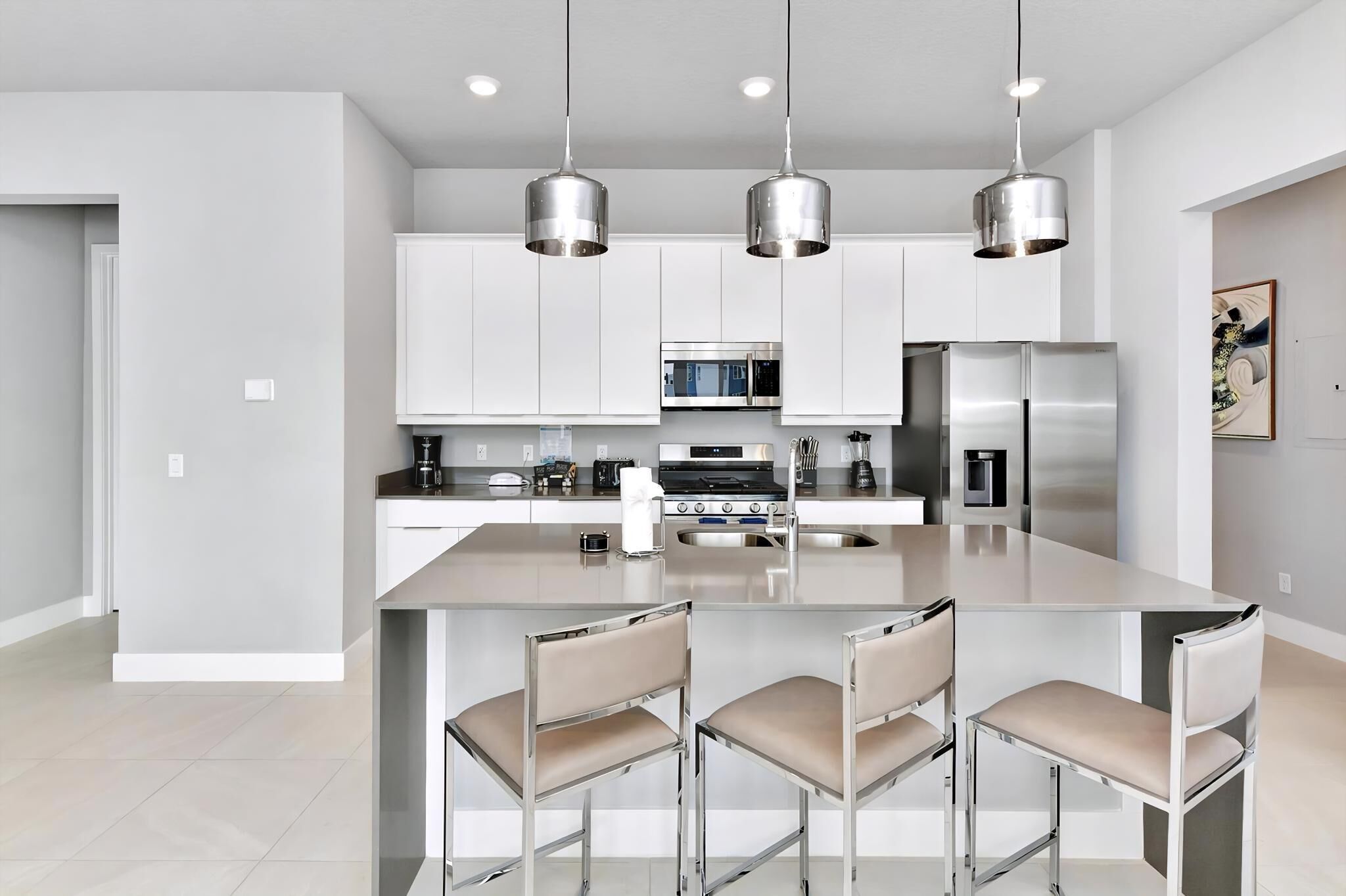 A modern kitchen with stainless steel appliances, a central island with bar stools, and pendant lighting.