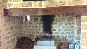 A stone-walled room with a fireplace, a flat-screen TV mounted above it, and a tiled floor.