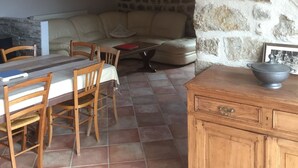 A dining area with a stone wall, wooden furniture, and a tiled floor.