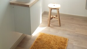 A modern bathroom with a skylight, a white sink, a wooden stool, and a yellow rug. - Ontdek de Kracht van de Rust, Dichtbij de Kust! (Veurne)