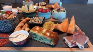 Verschiedene Speisen wie Brot, Käse und Wurst auf einer Holzplatte.