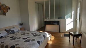 Ein Schlafzimmer mit Bett, Nachttischen, einem Schminktisch, einem Fenster und einer Heizung.